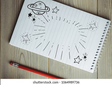 Space Doodle On Notepad Next To Red Pencil