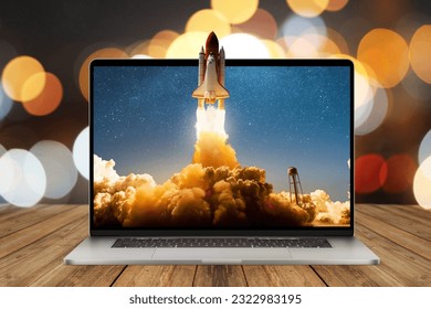 Space rocket shuttle with a cloud of smoke and blast lift off from a laptop on a working office desk with bokeh. Creative idea and startup. Successful business project. Rocket take off from display