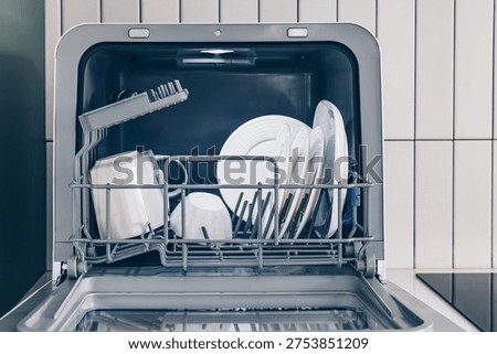 Space-Saving Solution: A Fully Loaded Compact Countertop Dishwasher with Clean Plates and Utensils Inside