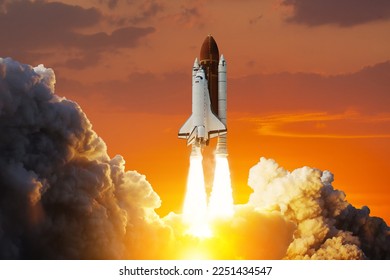 Spaceship lift off. Space shuttle with smoke and blast takes off into space on a background of sunset. Successful start of a space mission. Elements of this image furnished by NASA. - Powered by Shutterstock