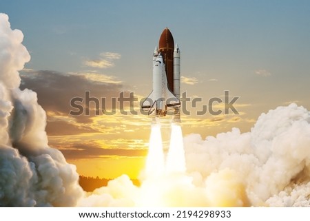 Spaceship lift off. Space shuttle with smoke and blast takes off into space on a background of sunset. Successful start of a space mission. Travel to Mars. Elements of this image furnished by NASA.