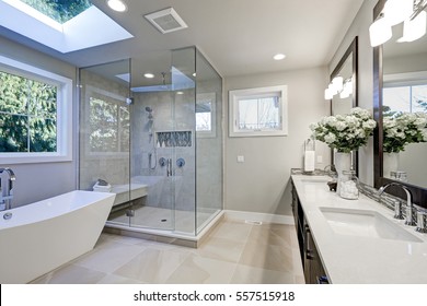 Просторная ванная комната в серых тонах с полом с подогревом, отдельно стоящая ванна, душевая кабина, двойная раковина и мансардные окна. Северо-Запад, США