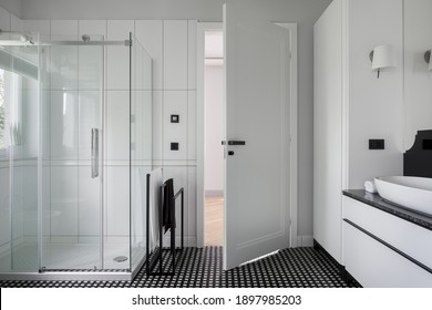 Spacious bathroom interior with shower and with black and white mosaic tiles on the floor