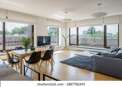 Spacious and bright living room with wooden floor, dining table and many window