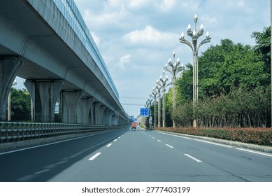 A spacious city highway alongside an elevated railway.