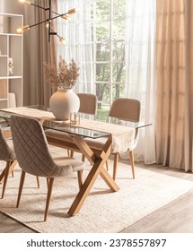 Spacious dining room in Nordic style showcasing a sleek glass tabletop, fabric quilted chairs, an intricate chandelier, and ambient sunlight filtering through sheer curtains, on a woven area rug.