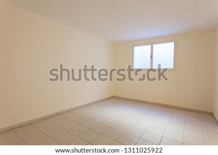 Spacious empty cellar. It consists of a window and a light tiled floor
