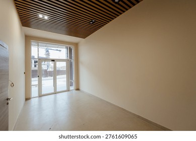 Spacious empty commercial interior featuring large windows and a wooden ceiling, with neutral walls and tiled flooring, ready for customization