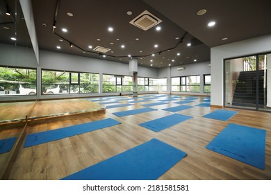 Spacious empty dance studio with many yoga mats on hardwood floor - Powered by Shutterstock