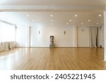 A spacious empty hall with columns and large windows. A gym with wooden floors for yoga and fitness classes. Interior design of the fitness center. A large room without furniture.