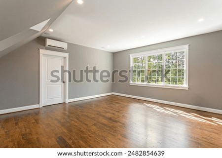 Spacious Empty Room With Large Window And Wooden Floors and Air Conditioning Unit