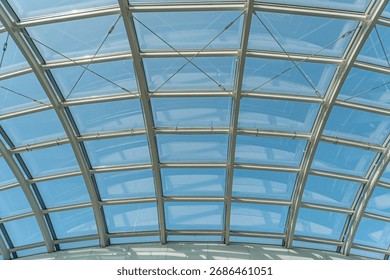 Spacious interior with a translucent, geometric ceiling structure made of tinted glass panels Natural light enters through the roof, casting soft shadows and creating a warm atmosphere contrasting c