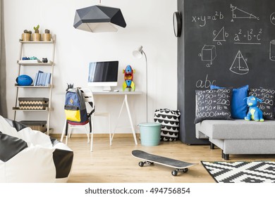 Spacious Kid Room With Wall Regale, Chair, Desk, Computer, Sack Chair, Carpet, Sofa, Chalkboard Wall And Pendant Lamp