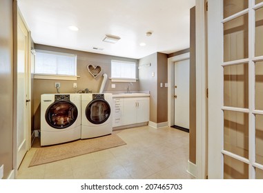 Spacious Laundry Room With Tile Floor And Light Grey Walls. Furnished With Modern Appliances