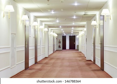 Spacious Light Hallway With Many Doors Leading Into Hotel Rooms.