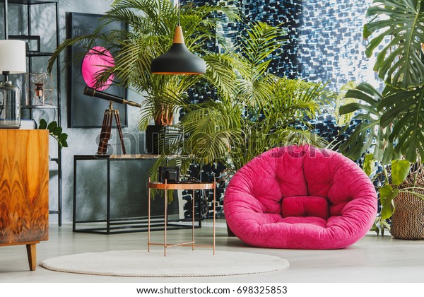 Spacious living room with pink plush armchair,\
telescope and exotic\
plants
