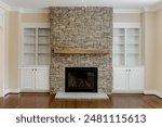 Spacious Living Room with Stone Fireplace and Large Windows Providing Light, Built in Shelves