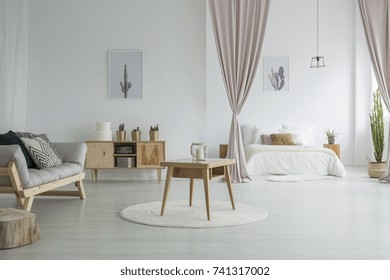 Spacious Living Room With Wooden Table On White Carpet, Rustic Cupboard And Grey Sofa Near Open Bedroom