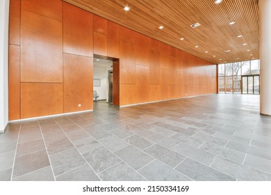Spacious lobby of a residential building with tiles on the walls and floor and a glass exit to the outside - Shutterstock ID 2150334169
