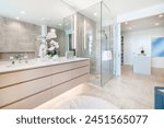 Spacious and luxurious primary bathroom ensuite in a modern and elegant waterfront condo free standing rectangular bath tub glass wall shower sinks rug counter top granite bathrobe and decorations