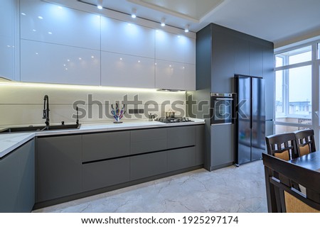 Spacious luxury white and dark grey modern kitchen interior with dining table