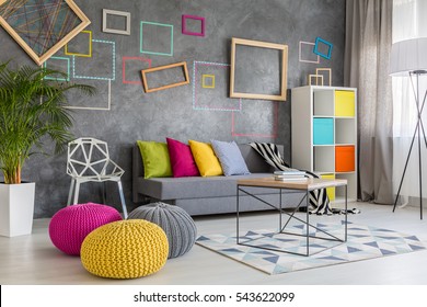 Spacious modern lounge with grey sofa and colorful pillows and poufs - Shutterstock ID 543622099