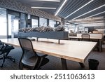 Spacious and modern open office area designed for productivity and collaboration. The space features long shared desks with ergonomic chairs and built-in storage drawers, creating working environment.