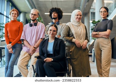 In a spacious and modern startup office, a diverse group of business colleagues, including a colleague in a wheelchair, collaborates and interacts, exemplifying inclusivity, diversity, and teamwork in - Powered by Shutterstock