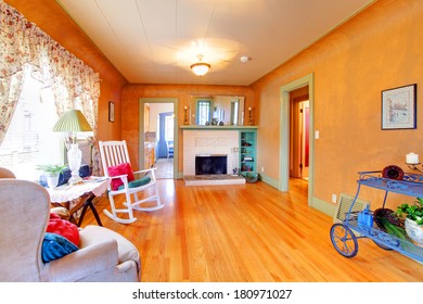 Spacious Orange Living Room With A White Fireplace, Rocking Chair, Table And Armchair