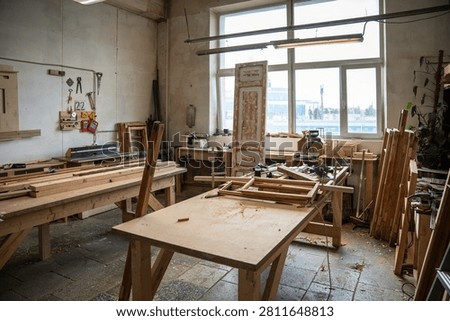 Spacious organized restoration workshop interior featuring worktable, instruments, tools and window, carpentry workroom filled with wooden materials and professional equipment for craftsmanship.