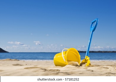 Spade And Bucket By The Water's Edge, Ready To Build A Sandcastle.