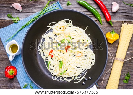 Spaghetti Aglio Olio e Peperoncino on Roasting Pan. Top View Italian Dish with Raw Cooking Ingredients on Wooden Background.