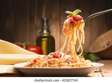 spaghetti with amatriciana sauce in the dish on the wooden table - Shutterstock ID 421827745