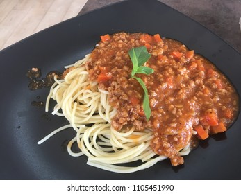 Spaghetti bolognese on black plate at restaurant