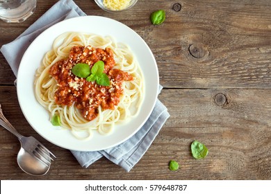 Spaghetti bolognese pasta with tomato sauce and minced meat, grated parmesan cheese and fresh basil - homemade healthy italian pasta on rustic wooden background