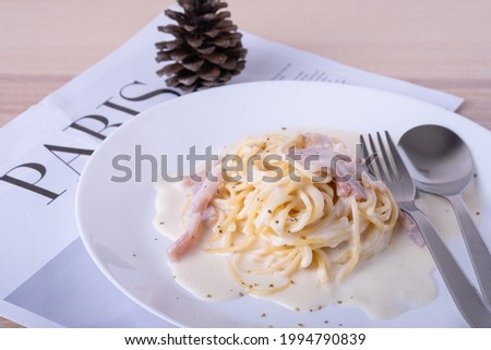 spaghetti carbonara on white plate with fork and spoon in spaghetti white cream plate on wooden table, Italian foodmenu concept with copy space for text. 