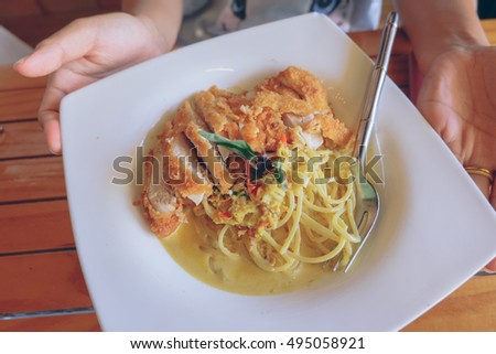 spaghetti and fish curry coconut milk and vegetable, with chicken fried steak,Fusion food.in woman hand.