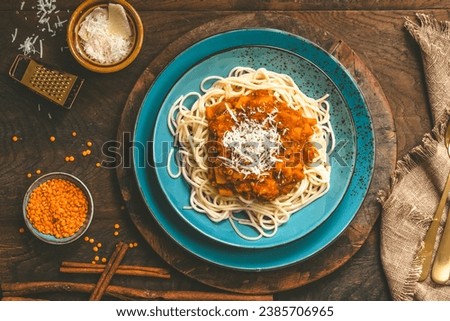 Spaghetti with homemade vegan Bolognese sauce made from red lentils and pumpkin on wooden background, turquoise earthenware, top view