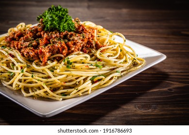 Spaghetti with marinara sauce, meat and parmesan on wooden table 