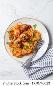 Spaghetti with meatballs, cheese and tomato sauce in a white dish.