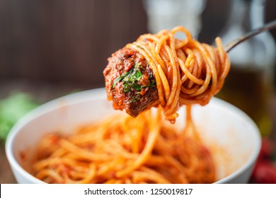 Spaghetti and meatballs with tomato sauce in white dish on wooden rustic board, Italian food closeup and top view. - Shutterstock ID 1250019817