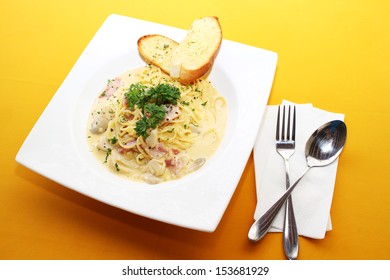 Spaghetti on white plate on yellow  table 