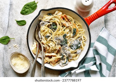 Spaghetti pasta with chicken, spinach and mushrooms in a skillet pan over light grey slate, stone or concrete background. Top view with copy space. - Powered by Shutterstock