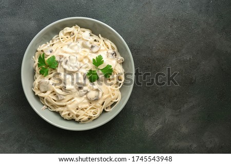 Spaghetti pasta with creamy mushroom sauce on a dark painted background. Italian traditional dish. Top view, copy space