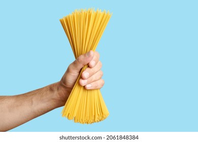 Spaghetti pasta in hand on a blank background. Raw Italian spaghetti before cooking and eating Italian food - Powered by Shutterstock