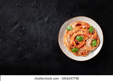 Spaghetti Pasta With Tomato Sauce, Grated Parmesan Cheese And Basil, Overhead Shot On A Black Background With Copy Space