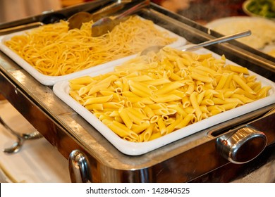 Spaghetti And Penne Pasta Steaming Hot In Serving Dishes On A Buffet