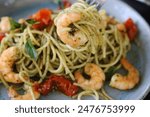 A spaghetti with pesto, confit tomatoes, and grilled prawns.