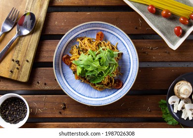 Spaghetti with Spicy Tune, Tomato Paste, Rocket Leaves and Lime Juice on Wood Table