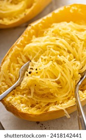 Spaghetti squash baked and pulled apart with two forks, ready to eat on a baking pan